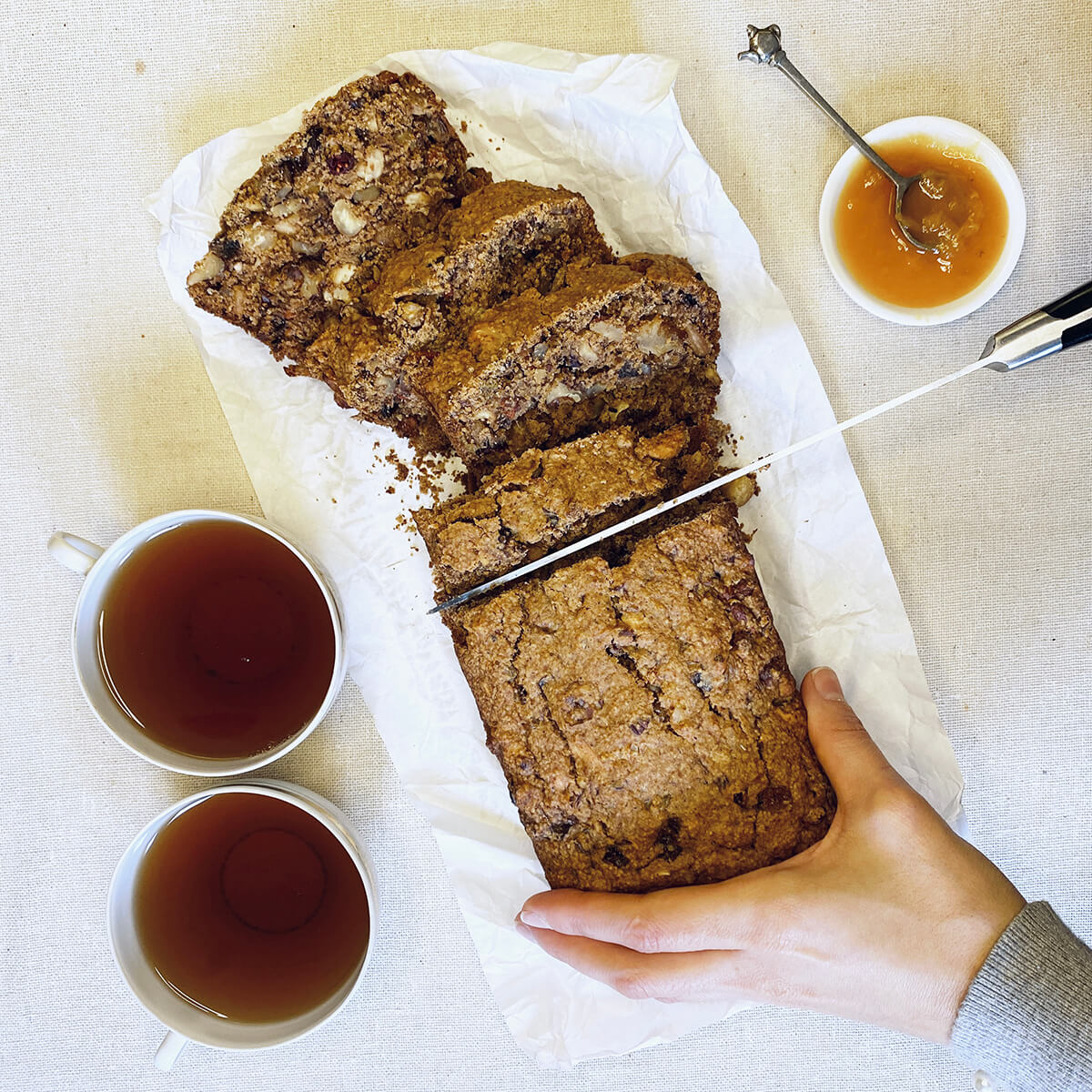 Mano cortando un Pan de Té y Frutos Secos Vegano