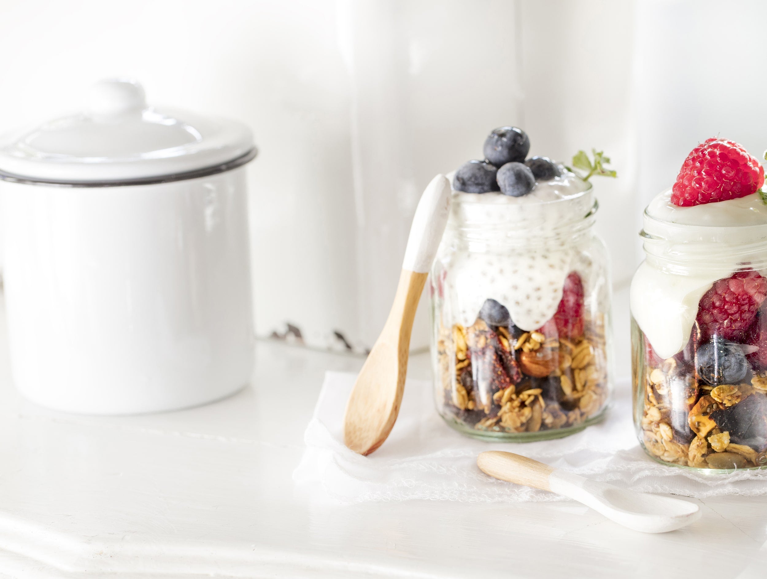 Azucarero blanco y dos vasos con granola frutos rojos y yogur